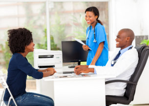 male doctor and female nurse talking with an adult woman smiling